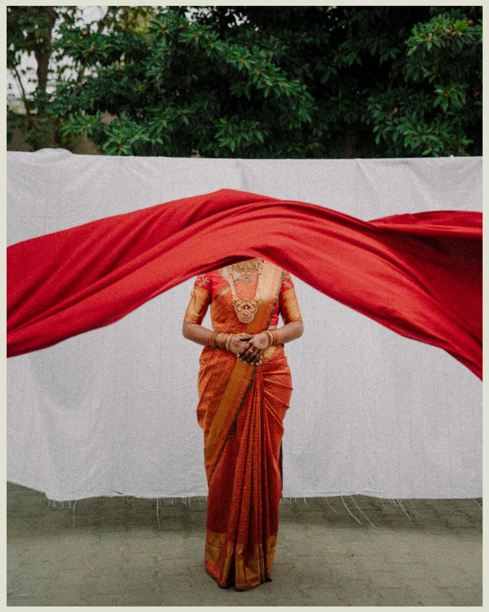 A bride framed by a flowing red wedding cloth
