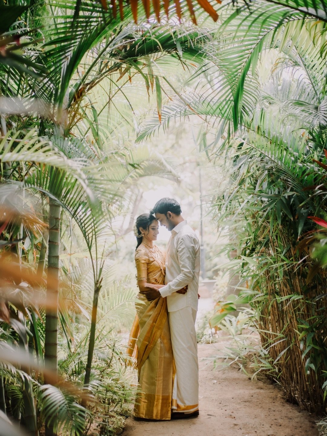 A couple standing together among lush tropical greenery